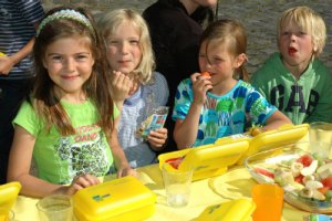 Vier Kinder vor ihren gelben Bio-Brotboxen beim Vespern.