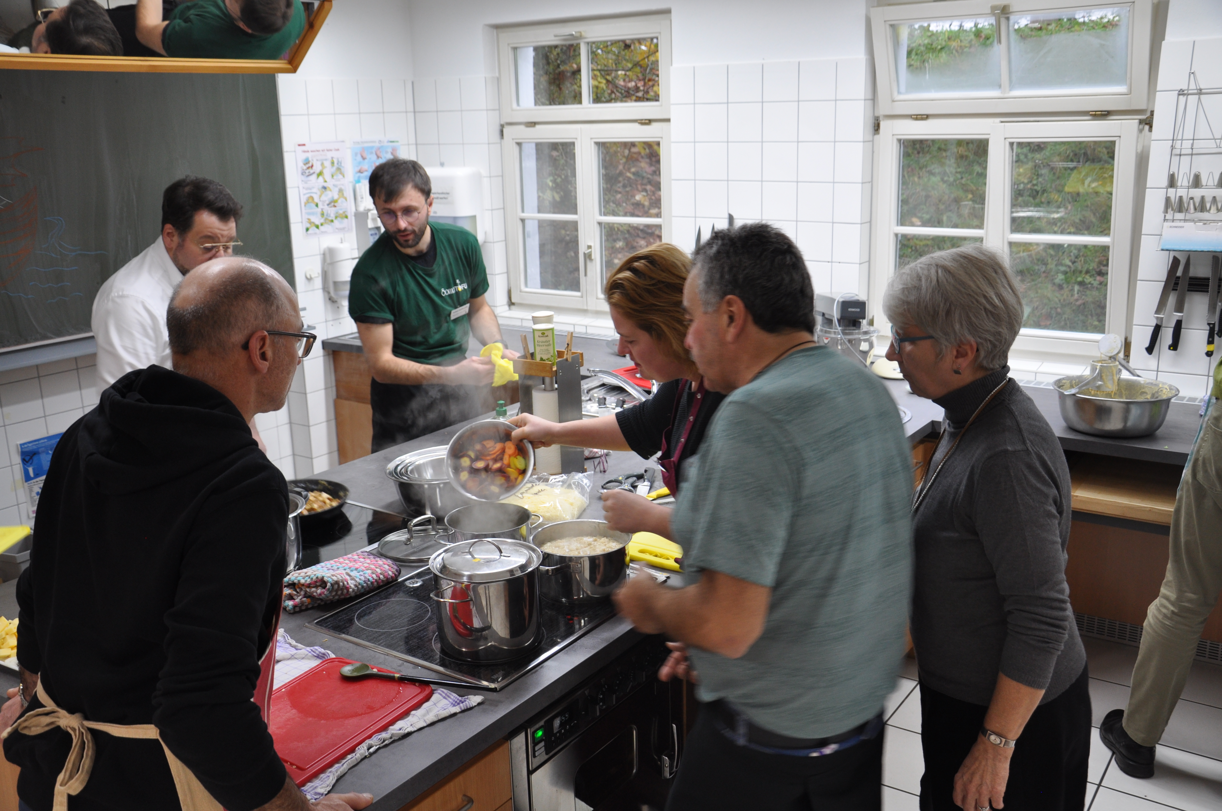 Teilnehmende der Küchensause stehen gemeinsam um die Kochinsel und kochen. 