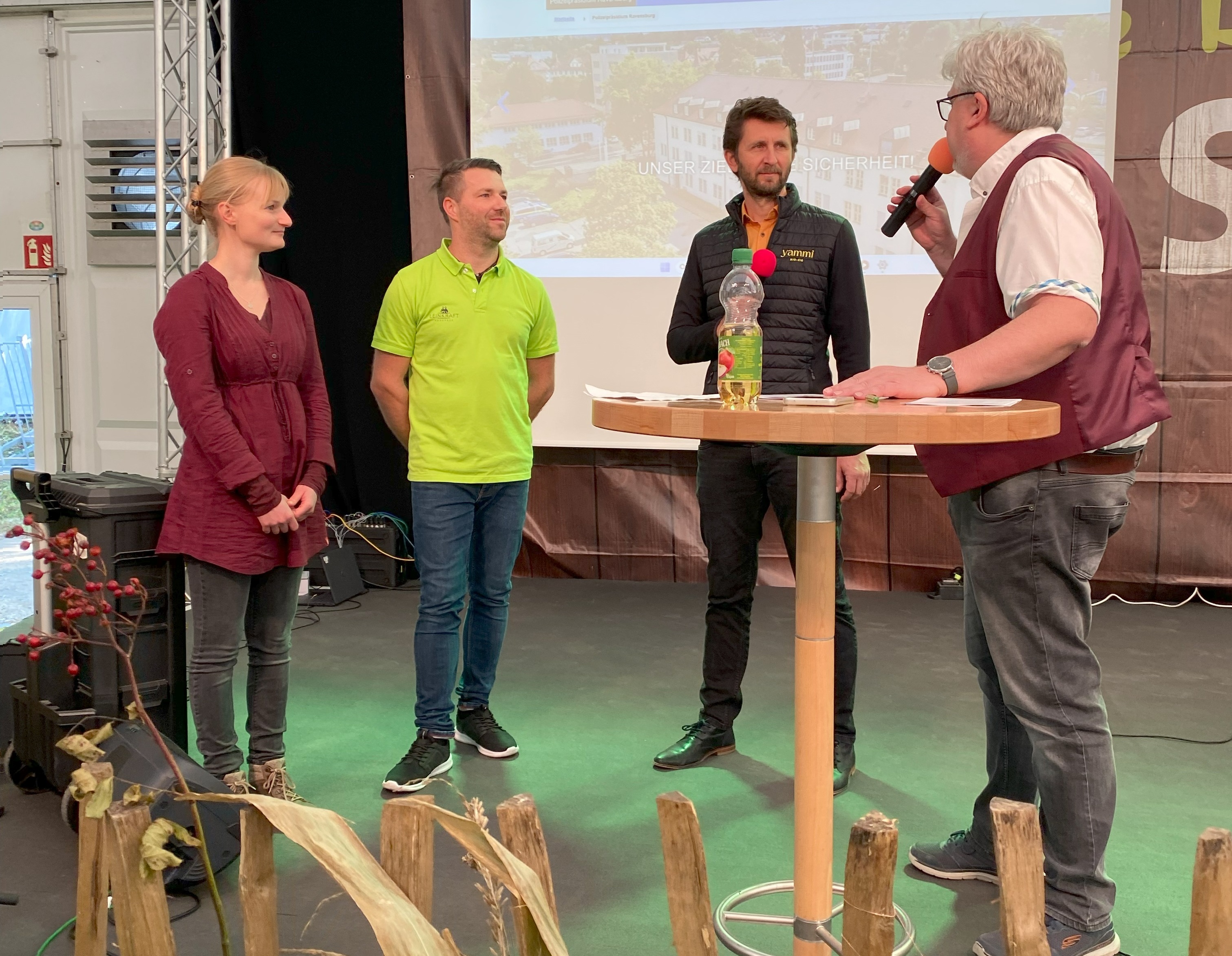 Vier Personen stehen auf der Bühne, einer spricht ins Mikrofon