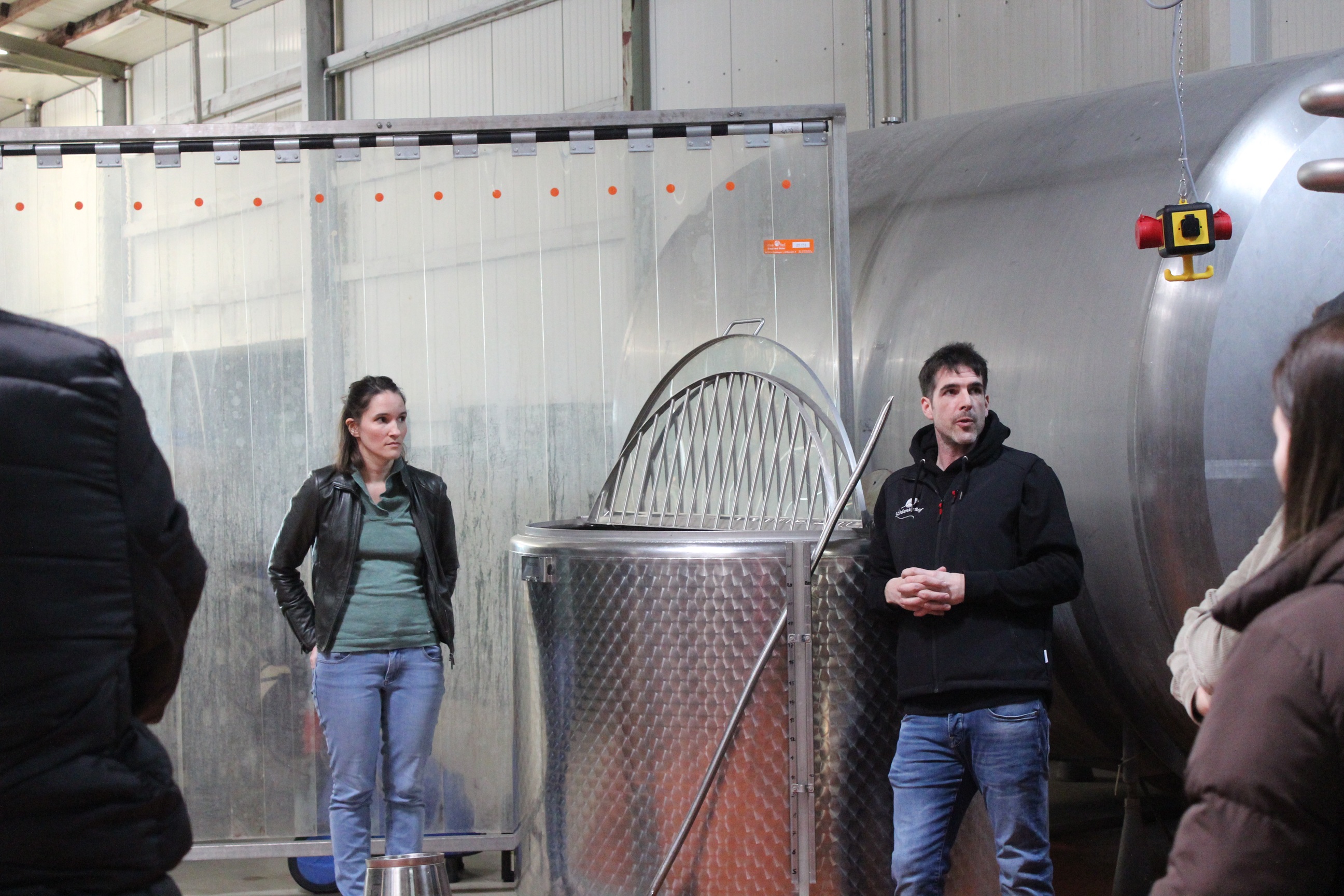 zwei Personen stehen neben zwei großen Tanks einer davon etwas kleiner und schauen in Richtung ihres Publikums