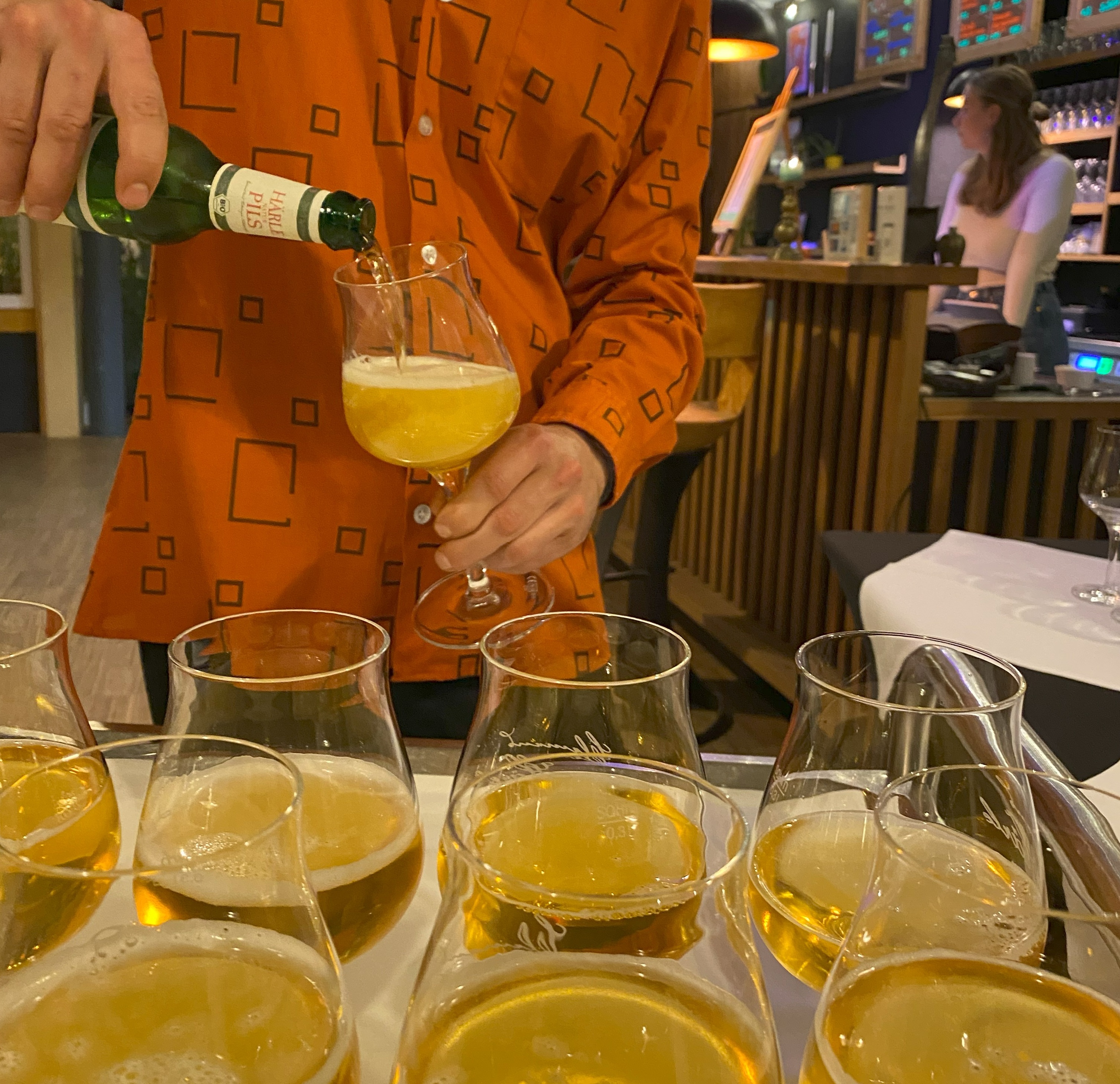 Es wird Bier aus einer Flasche in ein Glas gefüllt. Auf der grünen Flasche steht 