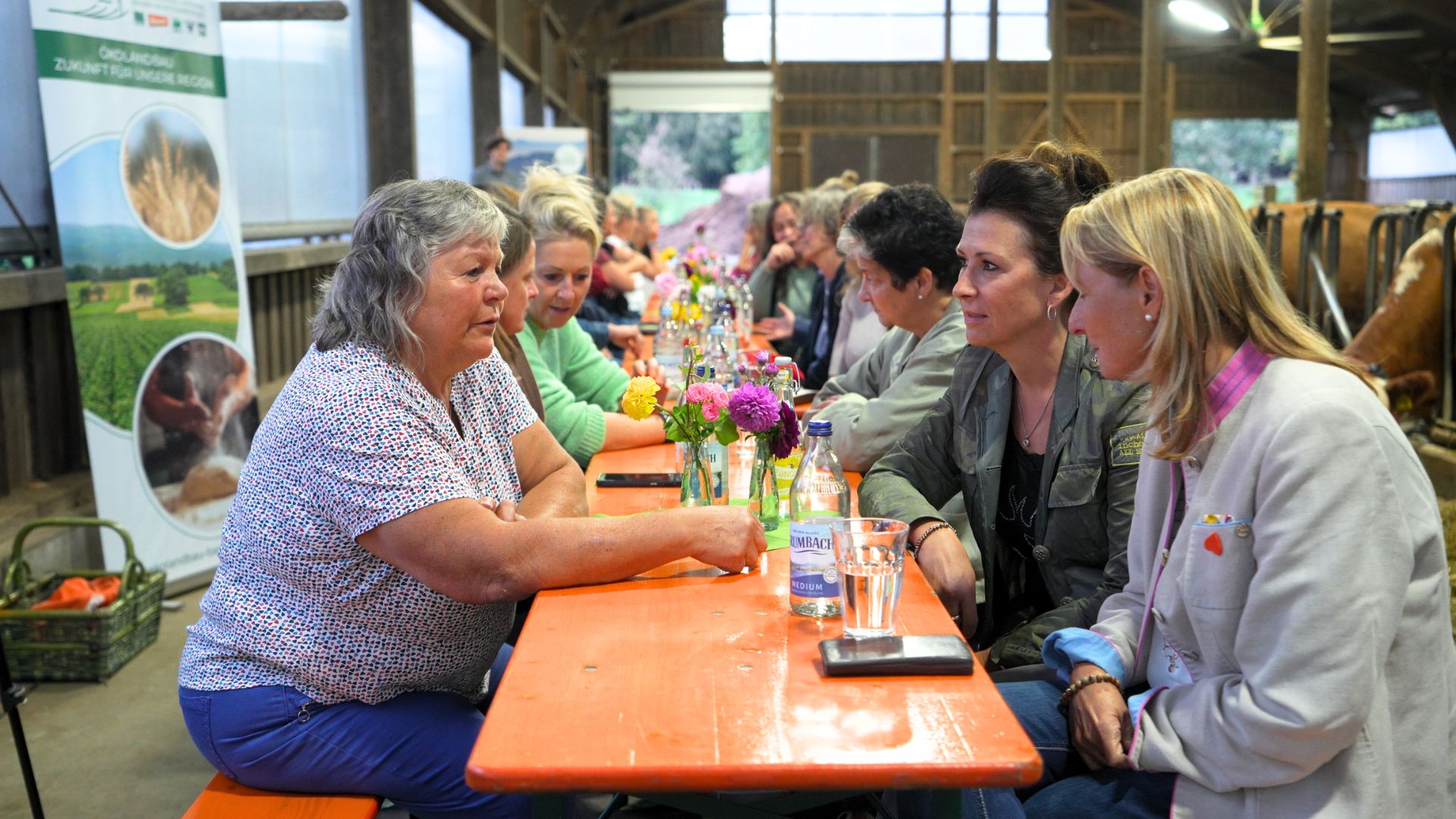 Frauen sitzen an einer langen Tafel und unterhalten sich 