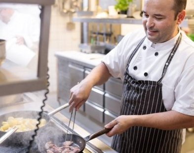 Koch des Bio-Restaurants Adler brät Fleisch an