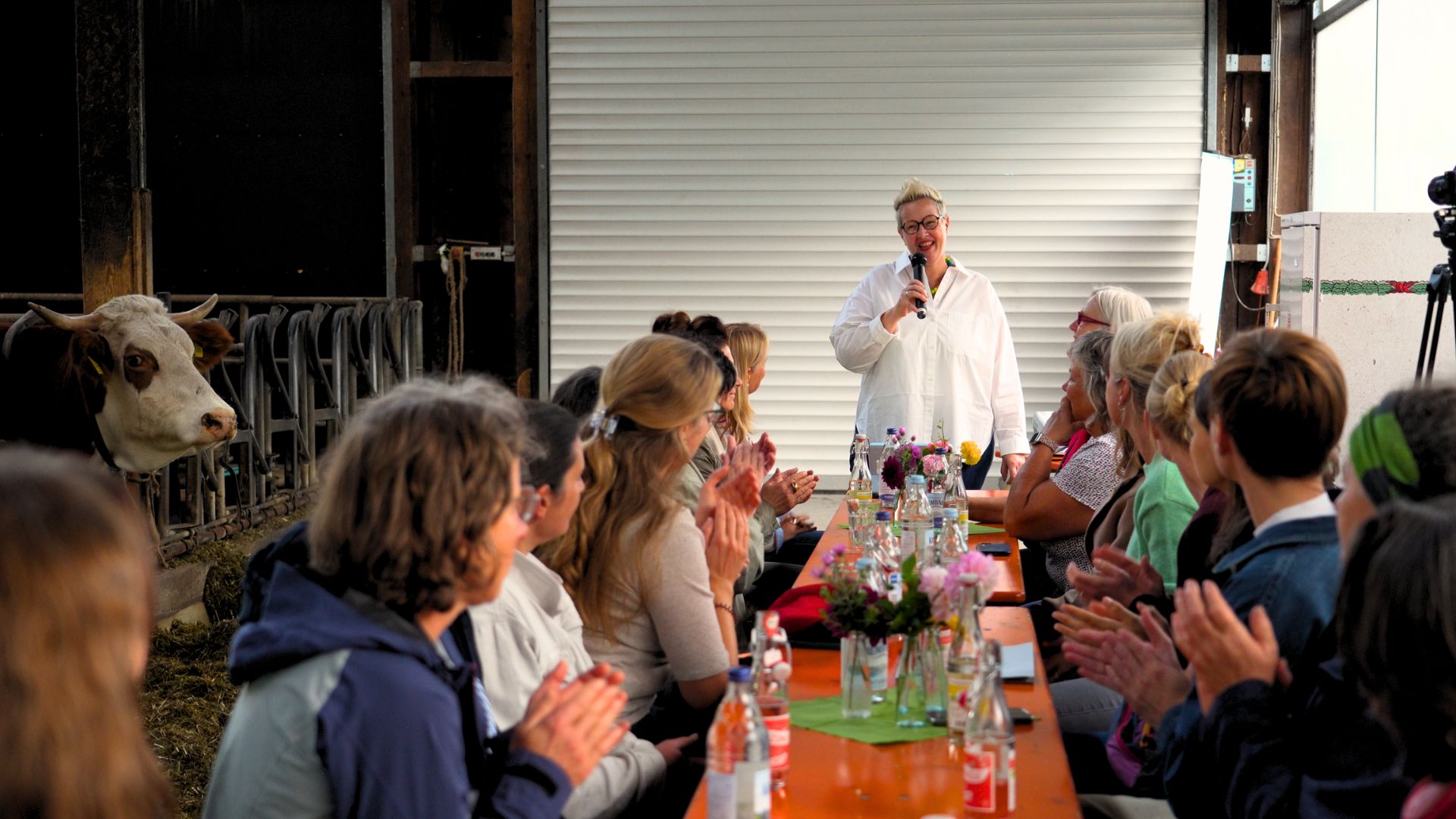 Eine Frau steht vor der Tafel und spricht. Die Frauen am Tisch klatschen